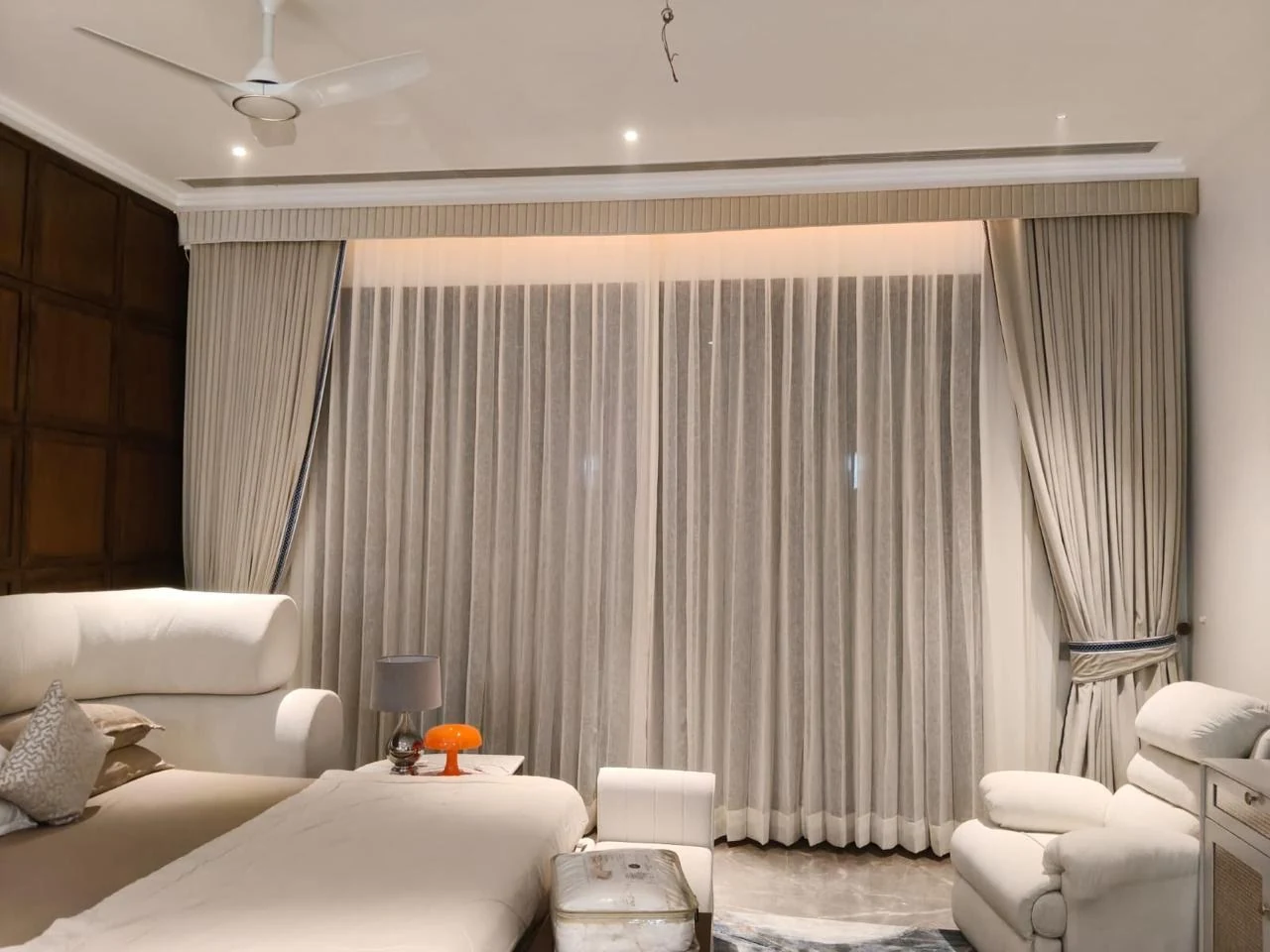Light curtains and layered drapes in a furnished living room.